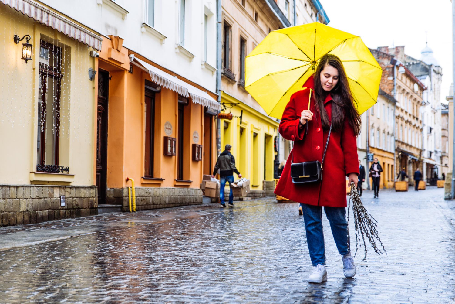 Smiling woman in red coat with yellow umbrella walk by city street.jpg